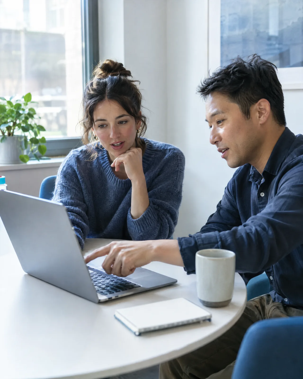 Two colleagues discussing a candidate on a laptop.