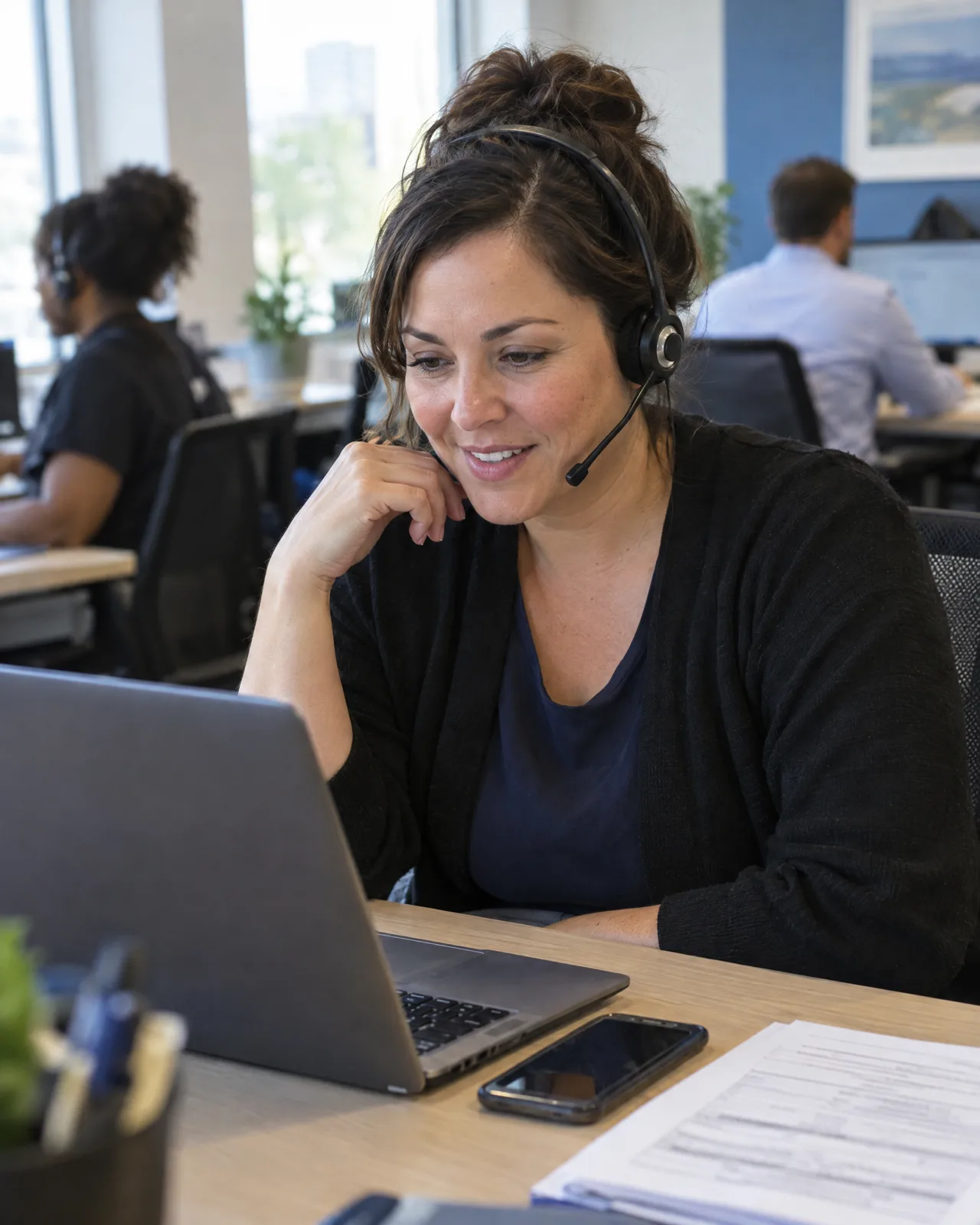 A recruiter with a headset reading a ranked shortlist on her laptop at a staffing agency desk.